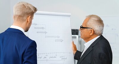 Vater mit Sohn bei einer Besprechung an einem Flipchart.